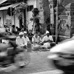 religious ceremony in Bali, at crossroads, as traffic streams by