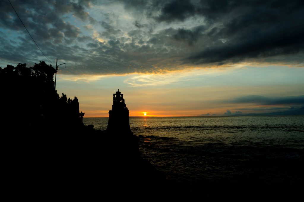 Balinese Temple on Lombok silhouetted against the sun setting over the ocean